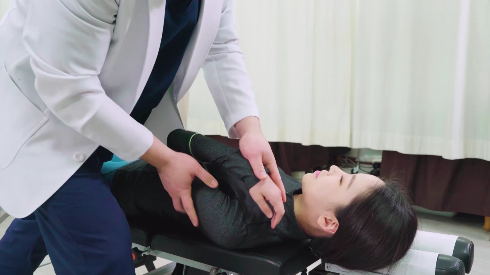원장이 환자의 등(흉추)을 손으로 짚어 굳은 마디를 바로잡는 모습